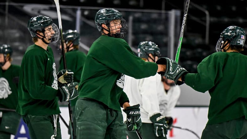 Minnesota Wild top prospect Charlie Stramel, center, bumps fists with Ryker Lee during hockey practice on Thursday, Sept. 25, 2025, at Munn Arena in East Lansing.